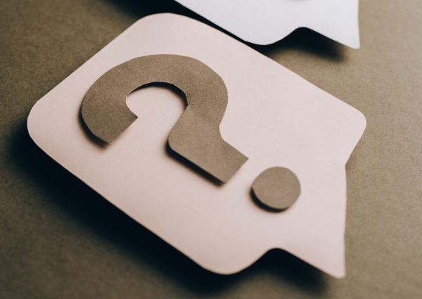 Two paper craft question marks on speech bubbles create a conceptual visual.